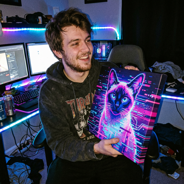 Tyler V. smiling candidly in a dark, messy, neon-lit gaming bedroom holding a frameless Digital Glitch Reality Siamese cat canvas illuminated by monitor glow